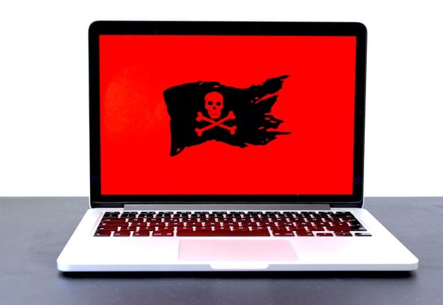 Laptop with jolly roger on a red background showing on screen demonstrating a need for antivirus